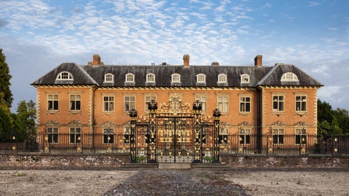 Golygfa o wedd ogledd-orllewinol Tŷ Tredegar, Casnewydd, o’r tu allan i’w gatiau haearn gyr du ac aur addurniadol.